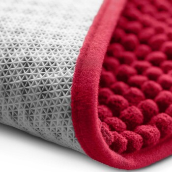 Nahaufnahme einer Haustiermatte mit einer strukturierten grauen Seite mit Pyramidenspitzen und einer plüschigen roten Seite mit abgerundeten Erhebungen.
