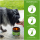 Ein schwarzer und grauer Hund schnüffelt an Snacks, die in einer Hand gehalten werden, neben einem offenen Glas mit der Aufschrift 'Köt & Grasfrei Leckerli' mit Dosierungsanweisungen.