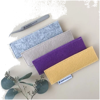 Vier rechteckige Filzetuis (grau, beige, lila, senf) mit einer 'PAWS & PATCH' Pinzette und Etikett, Eukalyptuszweig