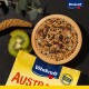 Drewniana miska kolorowych nasion dla ptaków stoi na ciemnej powierzchni z pokrojonym kiwi i żółtym opakowaniem Vitakraft oznaczonym "AUSTRALIA."