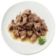 Ein Teller mit zartem, gewürfeltem Rindfleisch in einer herzhaften Sauce, garniert mit einem frischen grünen Blatt, das eine köstliche Option für Haustierfutter zeigt.