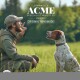 Mann in Outdoor-Ausrüstung hält eine Pfeife, sitzt im Gras und schaut auf einen braun-weißen Hund, Text „ACME Specialist Whistles Original Handmade“.