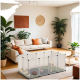 Ein gemütliches Wohnzimmer mit einem transparenten Haustier-Spielzaun mit kleinen Tieren darin, umgeben von einem beigen Sofa und Zimmerpflanzen.