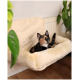 Eine dreifarbige Katze, die in einem weichen, cremefarbenen Haustierbett, das an einer Wand befestigt ist, entspannt, umgeben von grünen Pflanzen.