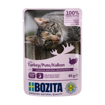 Pochette de nourriture pour chat avec un chat calico sur une surface en bois, étiquetée "Bozita" avec "Dinde" et "Sans céréales" en surbrillance.