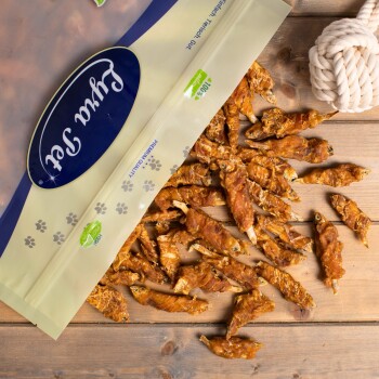 Eine Tüte mit getrockneten Fischleckerlis für Katzen, beschriftet mit "Premiumqualität", die auf eine Holzoberfläche fällt und verschiedene Fischformen zeigt.