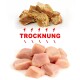 Bild von zwei Haufen Tiernahrung: getrocknete Fleischstücke oben, frisches Huhn darunter, beschriftet mit "TROCKNUNG" in fettem Rot für den Trocknungsprozess.