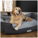 Ein golden retriever liegt bequem auf einem grau-schwarzen Hundebett mit einem Etikett, das "Scruff's" sagt, vor einem modernen Interieur.