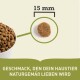 Haustierfutterkibble in einer Schüssel mit einer Nahaufnahme eines einzelnen Stücks, beschriftet mit "15 mm," und Text, der besagt "Geschmack, den dein Haustier naturgemäß lieben wird."