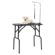 Ein hellfarbener Labrador-Welpe liegt auf einem schwarzen Grooming-Tisch mit einem Metallarm und einer Leinenbefestigung.