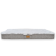 Ein plüschiges Haustierbett mit einer weichen weißen Oberseite und einer grauen strukturierten Basis, mit einem kleinen braunen Logo-Tag an der Seite.
