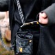 Nahaufnahme einer Person in einer schwarzen Jacke, die eine Haustier-Zubehörtasche mit einem Clip an ihrer Taille befestigt, mit einem Kordelzugverschluss.