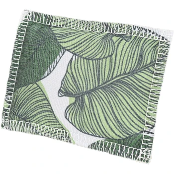 Une couverture pour animaux de compagnie avec un motif de feuilles vertes et des coutures blanches le long des bords.