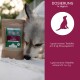 Eine Frau hält eine schwarze Katze neben einem großen Hund in einem Garten mit lila Blumen und zitiert Lena Huber zu Wolfsbacher Natur-Haustierprodukten.