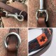 Nahaufnahmen einer braunen Lederleine für Hunde mit einem Metallclip und Ringen, mit einem dekorativen gewebten Abschnitt in Orange und Marineblau.
