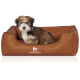 Ein kleiner, flauschiger Hund sitzt bequem in einem stilvollen braunen Haustierbett mit dem Logo "KNUFFELWUFF", das prominent auf der Vorderseite angezeigt wird.
