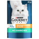 Chat fluffy blanc sur fond bleu, avec un emballage pour la nourriture pour chats Purina Gourmet, 85g, présentant "Erlesene Streifen in Sauce mit Kaninchen."