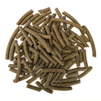 Ein Haufen dunkelgrüner, zylindrischer Tierleckerlis, die auf einem weißen Hintergrund verstreut sind und kleinen Sticks oder Kaustreifen ähneln.