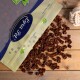 Eine Tüte mit Tierleckerlis mit der Aufschrift "Paw Pet" und einem blauen Logo, die kleine, quadratische, braune Leckerlis auf eine Holzoberfläche fallen lässt.