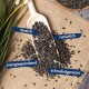 Eine Holzschaufel mit schwarzen Sonnenblumenkernen auf Jute, mit verstreuten Kernen und Etiketten: "ölreich," "natürlich," "energiespendend," "schnabelgerecht."