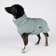 Ein brauner und schwarzer Hund, der in ein weiches, hellblaues Handtuch gewickelt ist, von hinten vor einem schlichten weißen Hintergrund betrachtet.