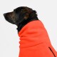 Ein schwarz-brauner Hund trägt eine leuchtend orangefarbene Fleecejacke, im Profil vor einem weißen Hintergrund gezeigt.