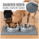Zwei Hunde, ein kleiner schwarzer und ein Golden Retriever, essen aus Edelstahlschüsseln auf einer grauen Matte. Der Text lautet: "Sauberer Boden dank hohem Rand."
