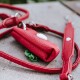 Roter Lederhalter für Hundekotbeutel mit einem weißen Knopf, begleitet von einer passenden Leine, die auf einer strukturierten Oberfläche ruht.