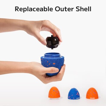 Hände halten ein blaues Haustierspielzeug mit austauschbarer Außenschale, schwarzer Deckel wird entfernt, Text "Austauschbare Außenschale" darüber.