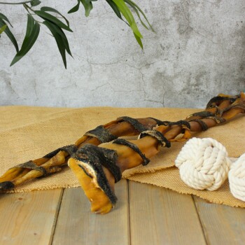 Eine Nahaufnahme von gedrehten natürlichen Kaustangen und zwei kleinen Seilspielzeugen auf einer strukturierten grauen Oberfläche, mit einer kleinen grünen Pflanze in der Ecke.