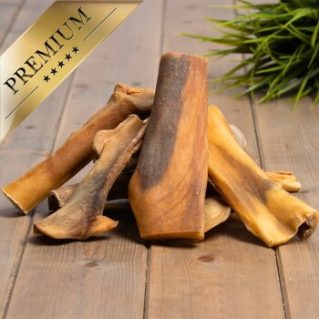 Ein Haufen hochwertiger Hundekauartikel auf einer Holzoberfläche, mit einem goldenen 'PREMIUM'-Label in der oberen linken Ecke.