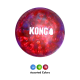 Balle jouet KONG translucide rouge pour chien avec picots surélevés et logo blanc «KONG» ; petites variantes bleue, verte et rouge en dessous sur fond noir.