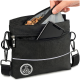 Eine Hand, die ein Hundeleckerli in eine schwarze Hundeleckerli-Tasche mit Reißverschluss und einem Logo steckt, mit einem Schultergurt und reflektierenden Details.