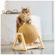 Un chat gris duveteux avec des yeux verts est assis sur une balle à gratter ronde recouverte de corde sur un support en bois, dans un cadre intérieur moderne.