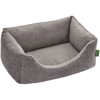 Orthopädisches Hundesofa Seattle grau S Graues Haustierbett mit einem plüschigen Innenraum und erhöhten Seiten, mit einem strukturierten Stoffaußenbereich und einem kleinen grünen Etikett.
