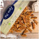 Eine Tüte getrockneter Fischleckerlis für Katzen, mit einigen verstreut auf einer Holzoberfläche. Die Tüte hat ein blaues Logo und sagt "Premium Qualität" und "100% natürlich."