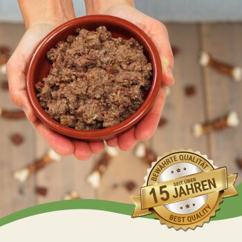 Eine Person hält eine braune Schüssel mit Haustierfutter, umgeben von Hundeleckereien, mit einem Abzeichen, das "Beste Qualität - seit über 15 Jahren" besagt.