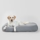 Ein entspannter Hund liegt auf einem weichen, grauen Haustierbett und zeigt Komfort und Stil in einem minimalistischen Umfeld.