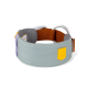 Ein stilvolles Haustierhalsband aus hellblauem Stoff mit einem gelben Logo-Patch, ergänzt durch einen orangefarbenen verstellbaren Riemen und grauen Akzenten.