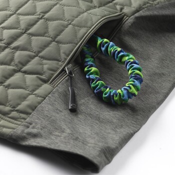 Eine Nahaufnahme einer grünen, gesteppten Haustierjacke mit Reißverschluss, die eine bunte Scrunchie-artige Leine in Blau und Grün zeigt.