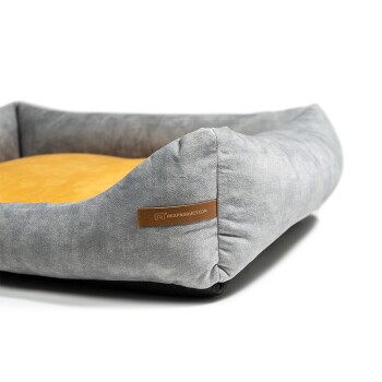 Graues Haustierbett mit einem gelben Kisseninneren, das ein braunes Etikett mit der Aufschrift "RexProduct.com" trägt.