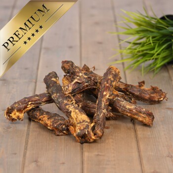 Premium-Hundekauartikel auf einer Holzoberfläche angeordnet, mit einer dekorativen grünen Pflanze im Hintergrund.