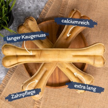 Vier große Hundekauartikel, die in einem Kreuz auf einem Holzbrett angeordnet sind, beschriftet mit den Texten: "langer Kauenuss", "calciumreich", "Zahnpflege" und "extra lang."