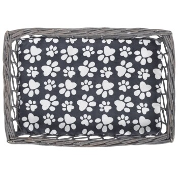 Ein gemütliches Haustierbett mit einem dunklen Stoff, der weiße Pfotenabdrücke und Herzen zeigt, in einem geflochtenen grauen Korb.