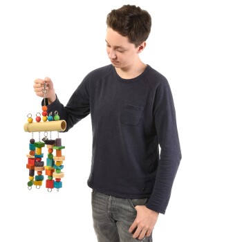 Eine Person in einem marineblauen Langarmshirt hält ein buntes Holzspielzeug für Vögel mit verschiedenen Formen und Perlen.