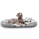 Ein grauer Weimaraner-Hund, der auf einem plüschigen, grauen Haustierbett mit einem kleinen Kissen entspannt, vor einem weißen Hintergrund.