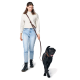 Eine Person in einem hellen Pullover und blauen Jeans führt einen schwarzen Labrador an der Leine, lächelnd, während sie gemeinsam spazieren gehen.