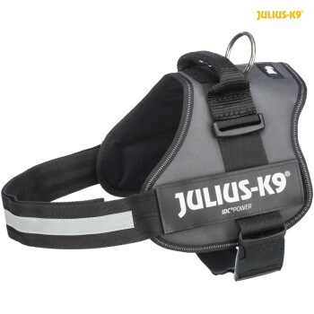 Ein schwarzes Julius-K9 IDC Power Hundegeschirr mit reflektierenden Streifen, das einen stabilen Griff und einen Metall-D-Ring für die Leinenbefestigung aufweist.