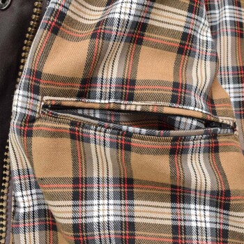 Nahaufnahme eines braun-schwarz-weiß-roten karierten Stoffes mit Reißverschlusstasche, wahrscheinlich Teil einer Hundejacke.