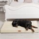 Ein schwarz-brauner Dobermann liegt bequem auf einem cremefarbenen Hundebett in einem stilvollen Schlafzimmer, mit einem weißen Bettgestell im Hintergrund.